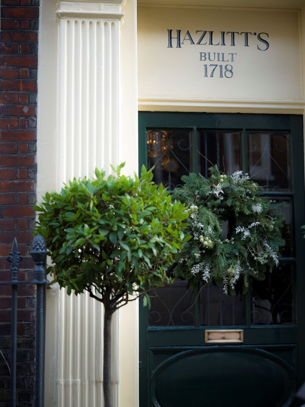 The entrance to Hazlitt’s hotel with a festive evergreen wreath hung on the dark green door beneath the sign “Hazlitt’s Built 1718.”